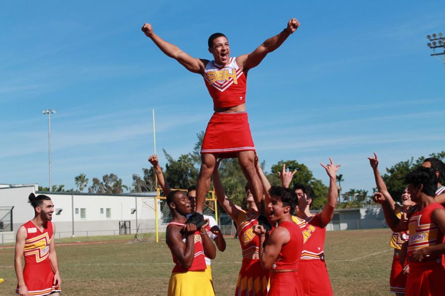 In this picture, Joel Pardilla,  is in a pyramid cheering. 