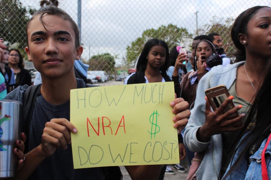 Student holding up his sign that says How much NRA money do we cost 