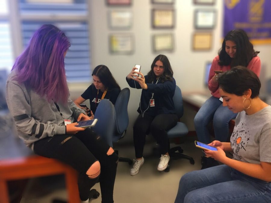 Teens on their phones, unaware of the fact that Mark Zuckerberg is selling the information they put up.