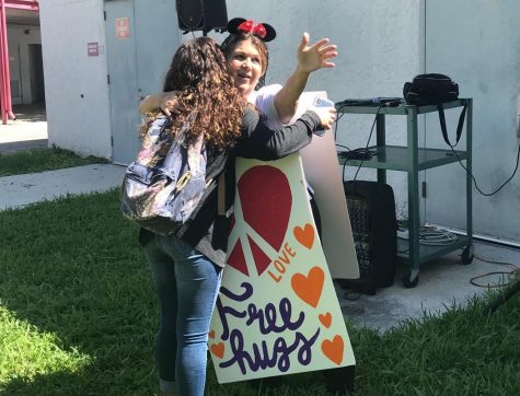Ms. Adriana spreads peace and love as she offers free hugs to students . Student Nicole Rios gives in to the love .