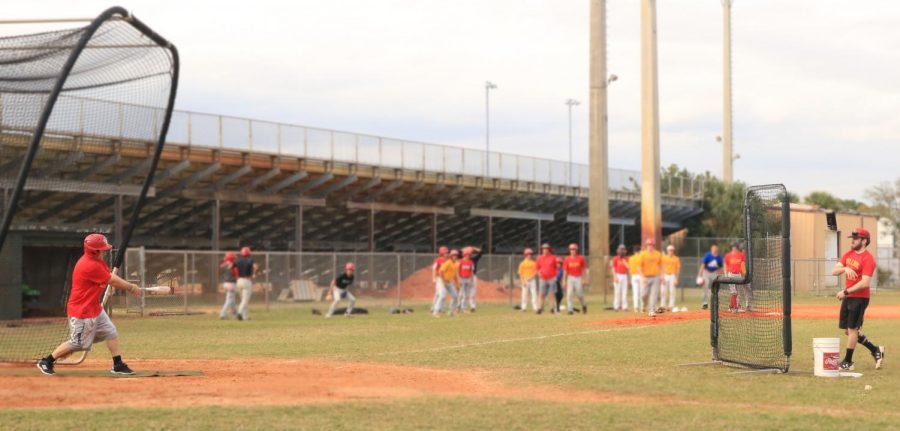 Coach Eckert bats while players practice fielding and baserunning.
