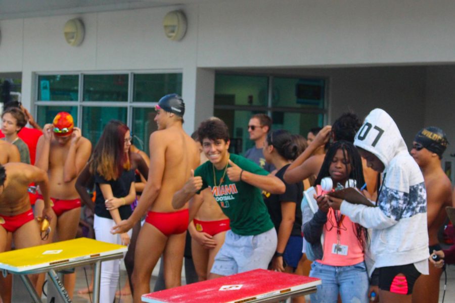 Michael Gonzales (12th) volunteers at the swimming competition at South Broward on October 10, 2019. The senior volunteered by timing the swimmers laps and cheering the team. Skys out thighs out, said Michael.