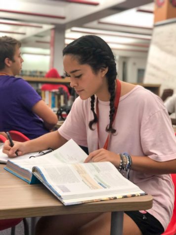 Senior Almendra Gutierez reading her textbook in the South Broward High School  library.