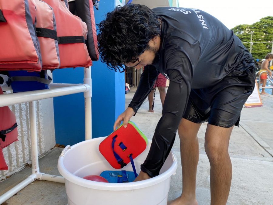 Juan Rubio, 19, sanitizes pool equipment for his next swim class to use.