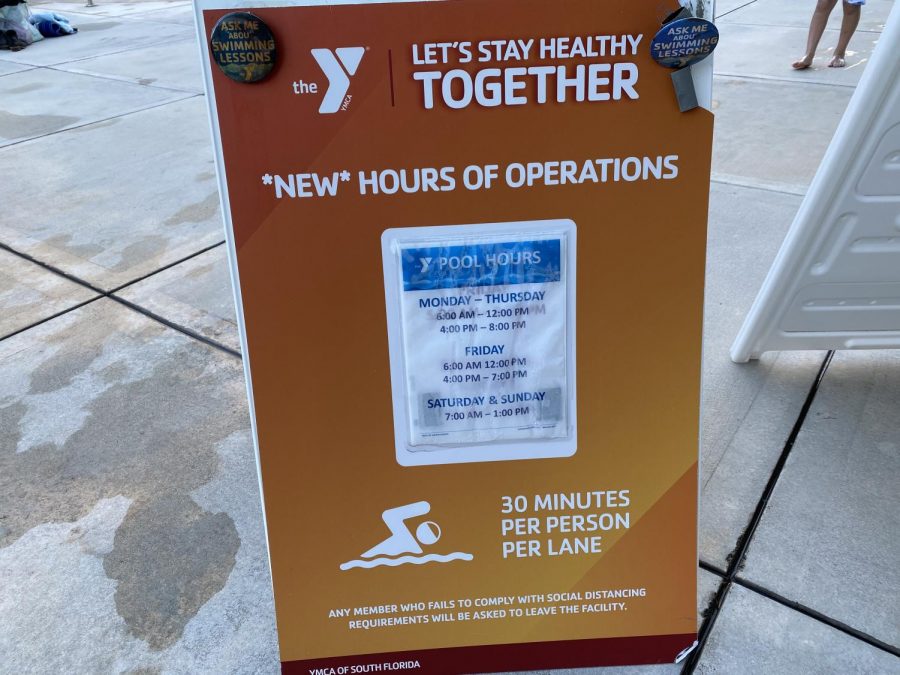 A sign on the pool deck indicating the new hours for the pool and 30 minute time limit per person because of COVID-19.
