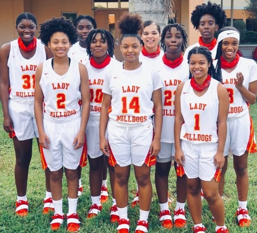 The girl basketball players stand together to take a photo before a game.
