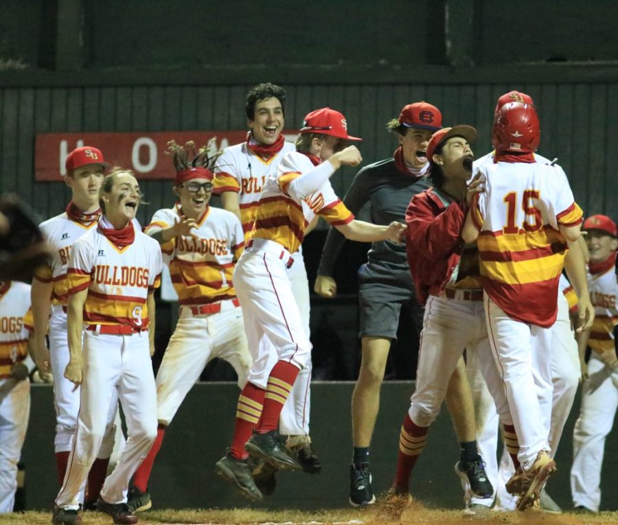Junior Lucas Scimeca (15) jumps for joy as hes mobbed by teammates and scores the game-winning run against Cooper City on February 22, 2021.