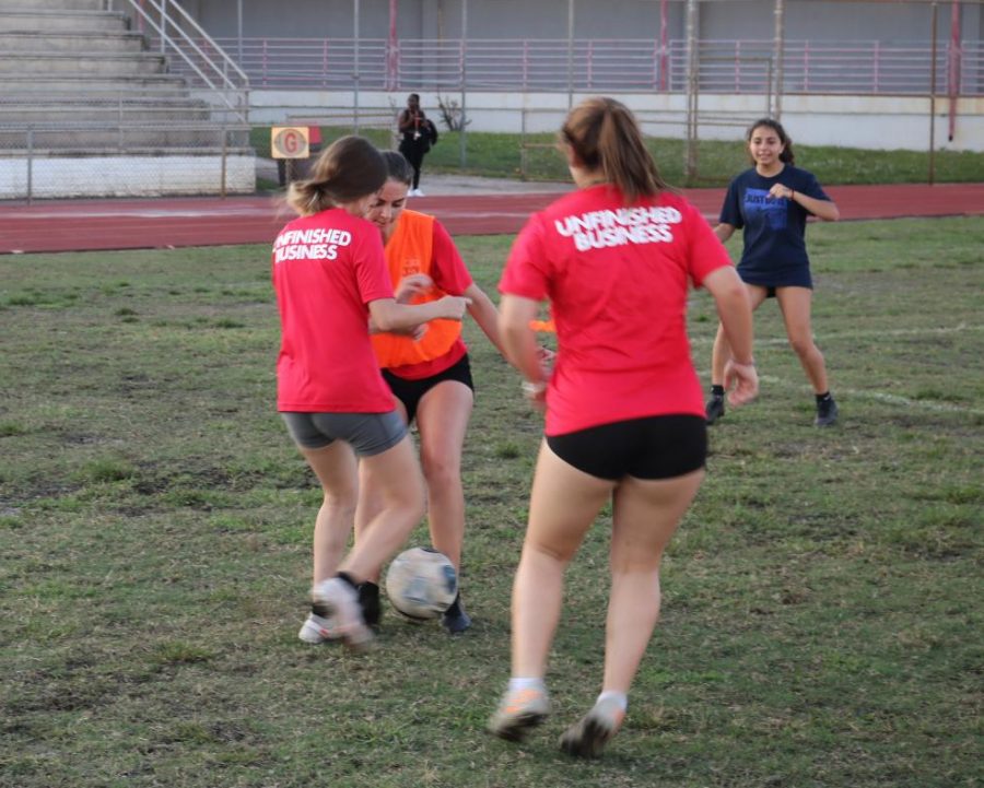 Three girls from the soccer team practicing hard at there home field.