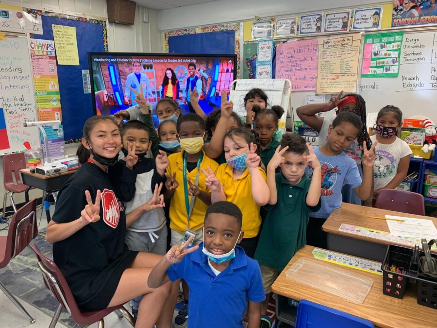 Latinos in Action student, Emily Betancour, poses with her elementary students at Oakridge Elementary School by giving peace signs. 