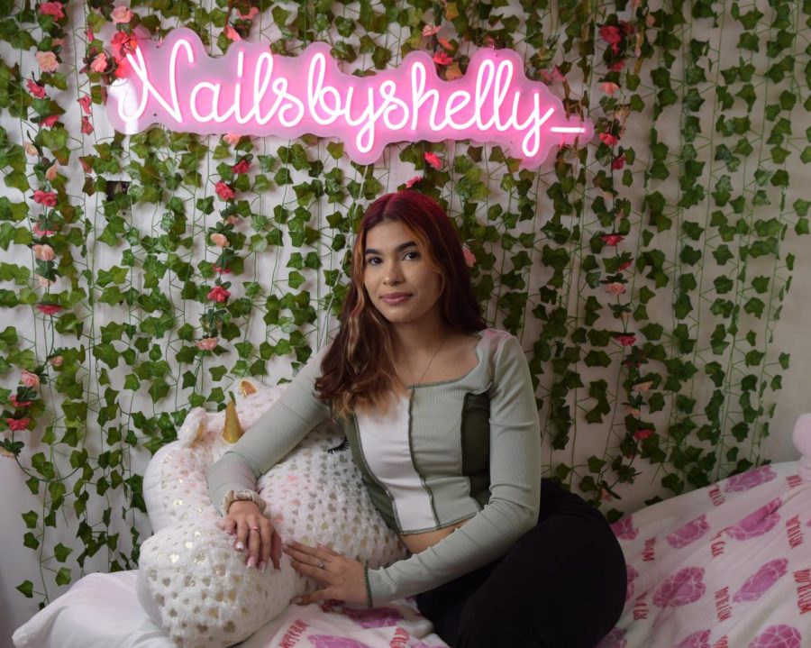 Nail+technician+and+small+business+owner+Shelly+Estrada+poses+in+her+salon+beneath+a+neon+sign+of+her+business+Instagram+account+name.+Estrada+and+her+mother+recently+opened+Purple+Touch+Beauty+Salon+in+downtown+Hollywood.