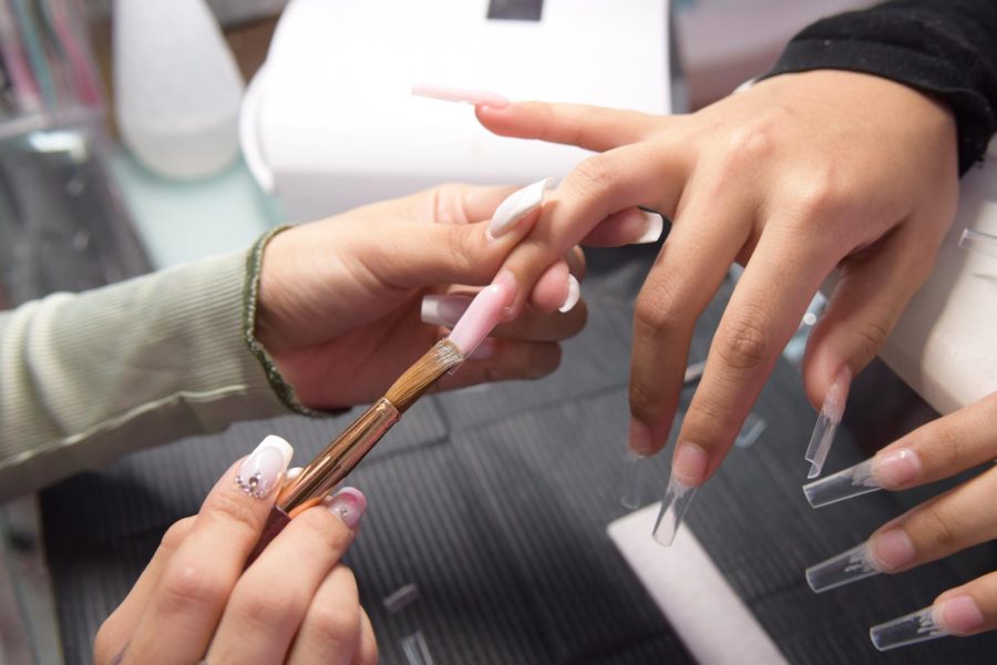 An acrylic top coat is used to adhere a clear plastic nail extension to the nail bed. From there, Estrada uses it as her canvas to create works of art you can wear on your hands. 
