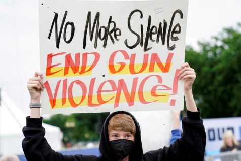 A student creates and holds up a poster in protest to end gun violence.