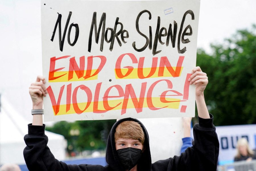 A+student+creates+and+holds+up+a+poster+in+protest+to+end+gun+violence.