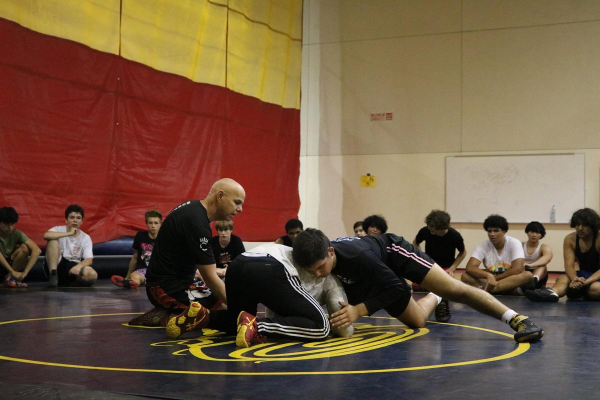 Coach Major is demonstrating a new move using two returning wrestlers during a practice.