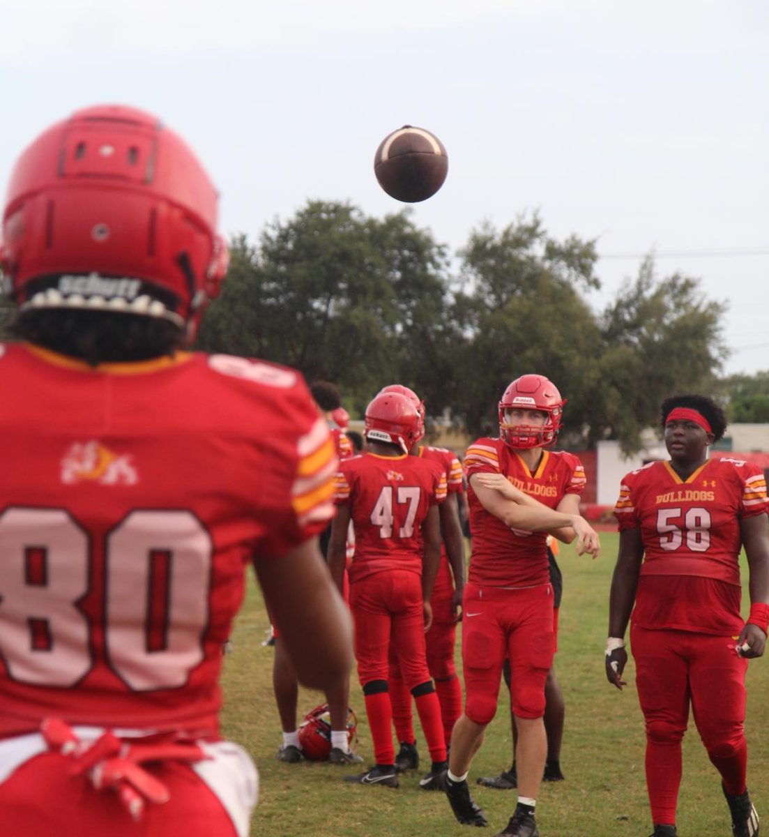 Members of the Bulldogs Varsity football team warm up on the sidelines before a home game. 