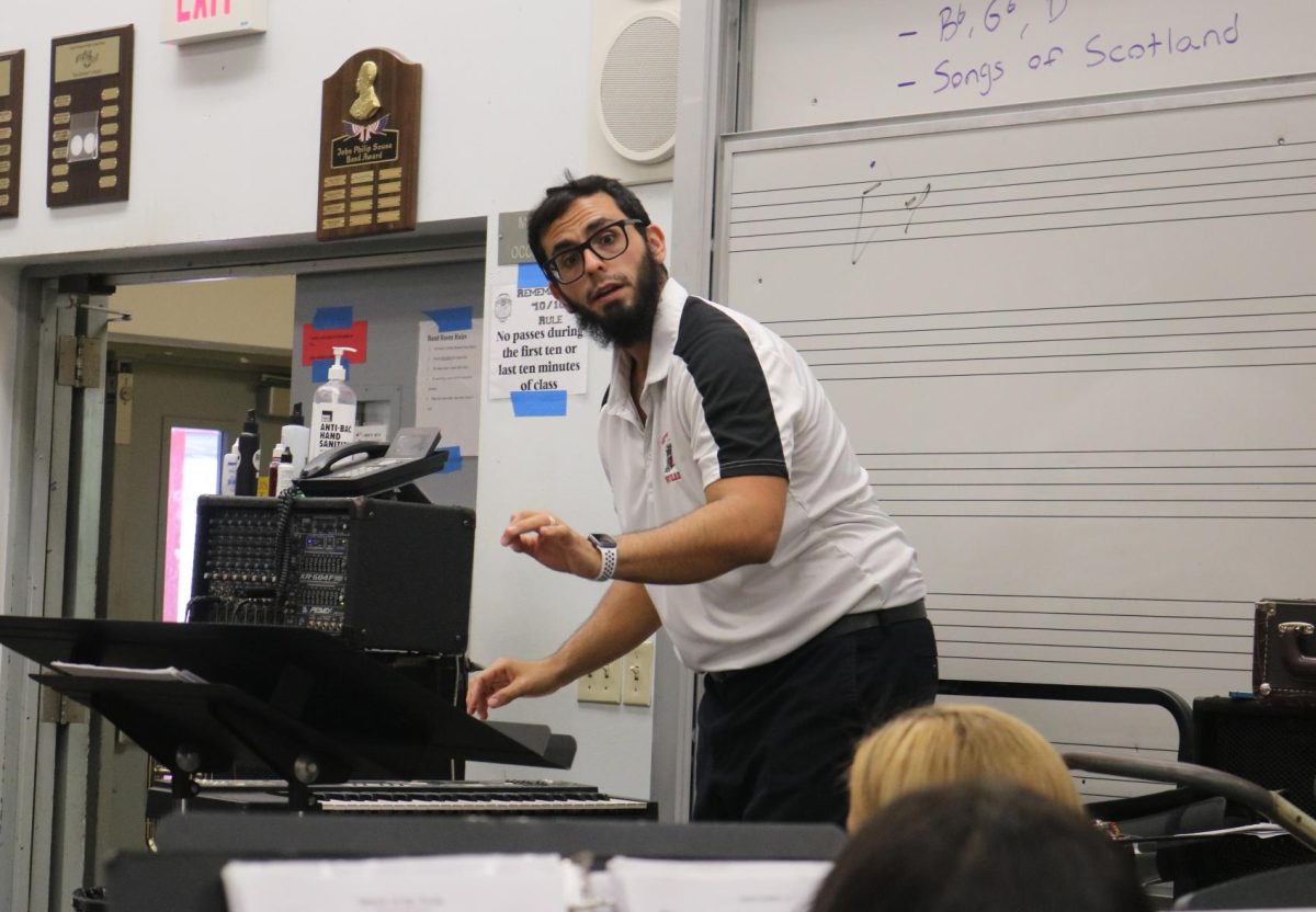 Band director Victor Villaoduna carefully directs his band student as they play their instruments in a harmonizing ensemble.  