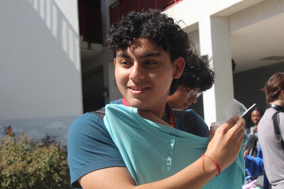 SBHS junior, Christopher Castro Rojas, admires a teal shirt while asking his friends opinion at the very first school thrift store during A lunch.