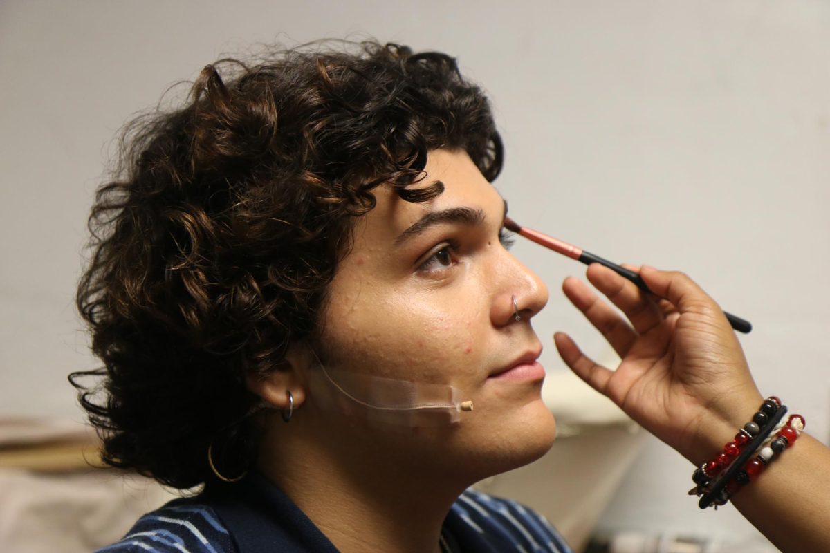 Noah Alejo as Damian Leigh in the Mean Girls Musical gets his make-up done backstage before on stage performance.