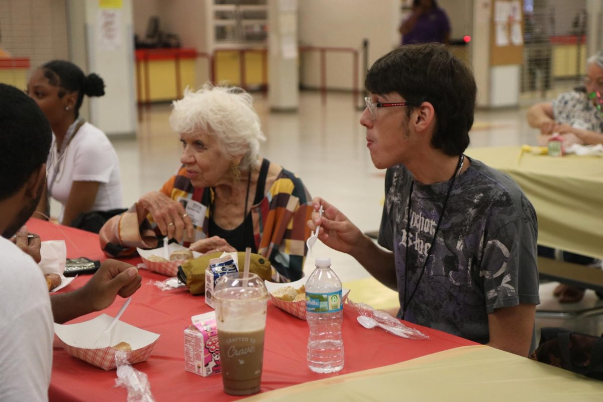 SBHS student Holden Miller takes a seat with his Grandmother Mrs. Miller to eat their breakfast provided from the school while they talk and enjoy the event set up by the school.