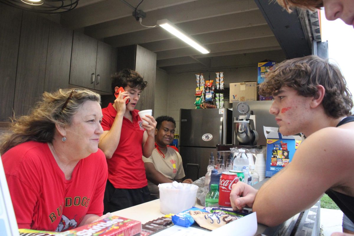 SBHS student Kai ___ ordering food from Mrs. ___ at tailgate.