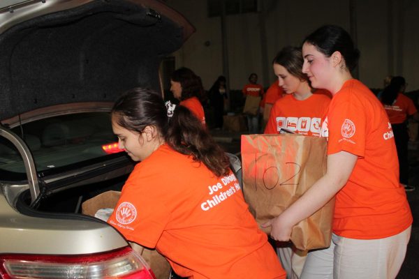 Anabella Hernandez, Seraphina Wagner, and Emma Keffer load bags full of goods into a families trunk.