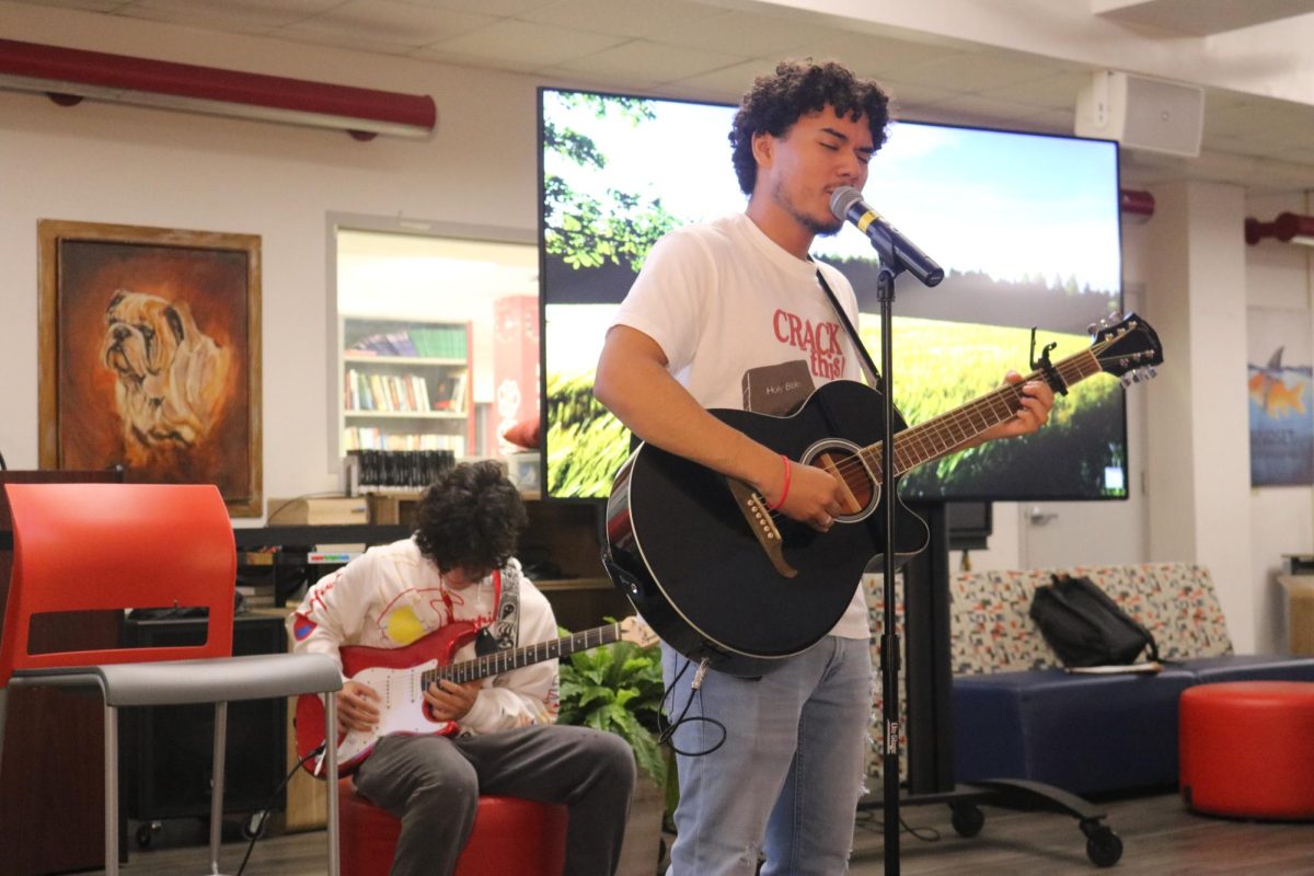 Brandon Villa sings an original song called "Away From Home" as Kai Bruestle strums notes in the back with his electric guitar.