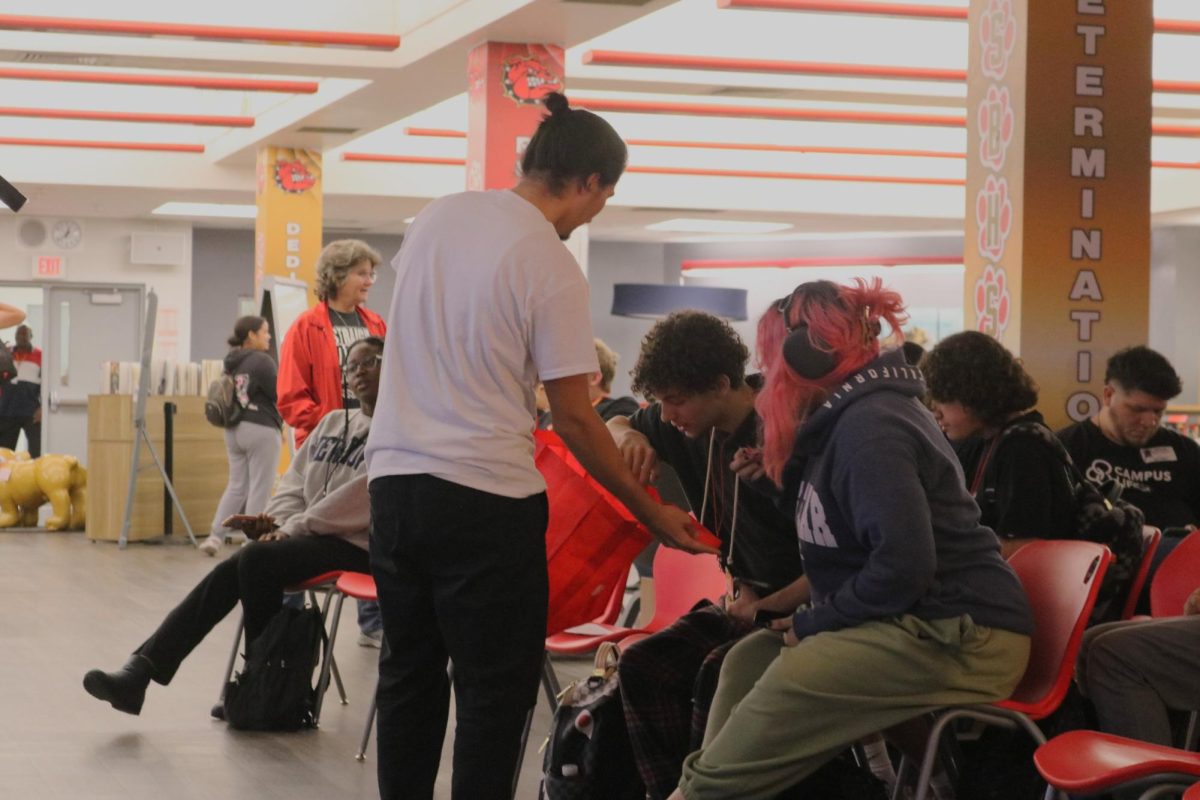 Maximo Sequi hands out candy to the students while waiting for the media center to fill up with more students before they perform their original songs and raps.