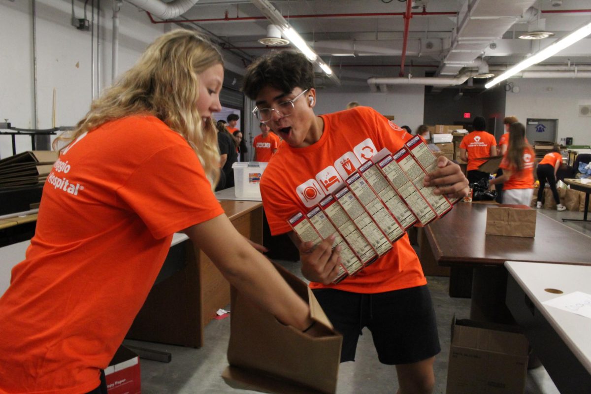 Athena Hawn and Jorge Zamudio prepare a bag with supplies and food to go hand them out to families in need for the harvest drive event.