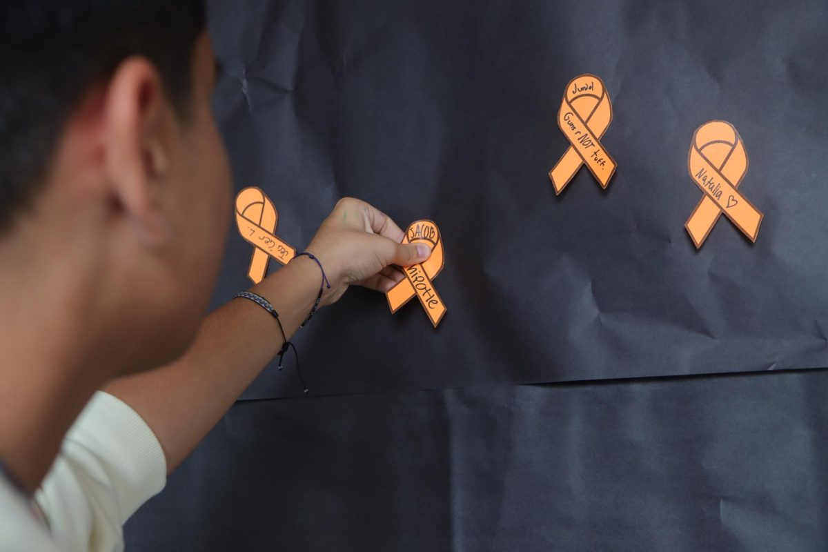 Sophomore Jacob Campo places an orange paper ribbon to show his support for the school campus efforts and activities.