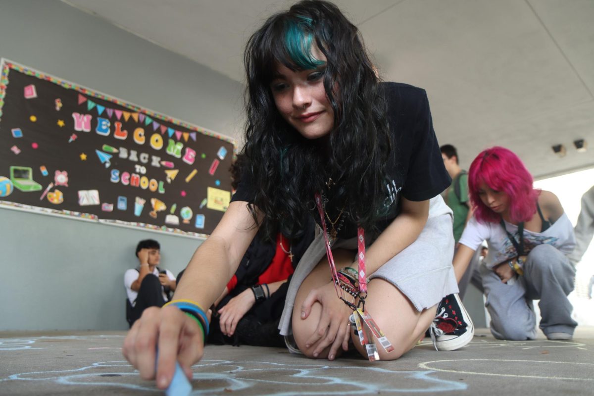 Junior Ava Beattie sketches on the pavement with calk, showing their support for the efforts of the end gun violence actions.