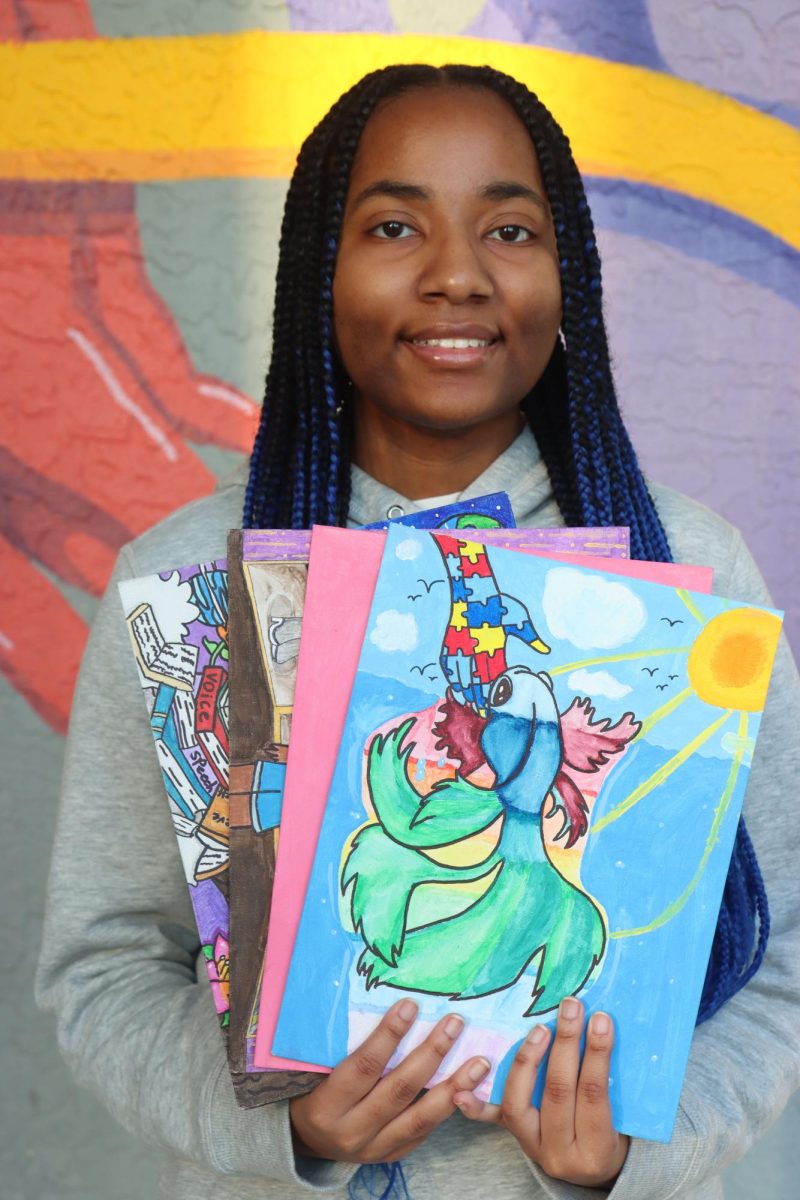 AP art student Na'Shia Oliver poses with several of her painting. Despite her autism, Oliver has managed to thrive in high school.