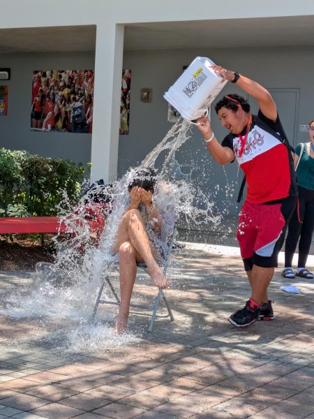 Curling into a ball to shield herself from the splash, Julicia Gamez braces as Nicklaus Cochrane dumps a gallon bucket of water on her.