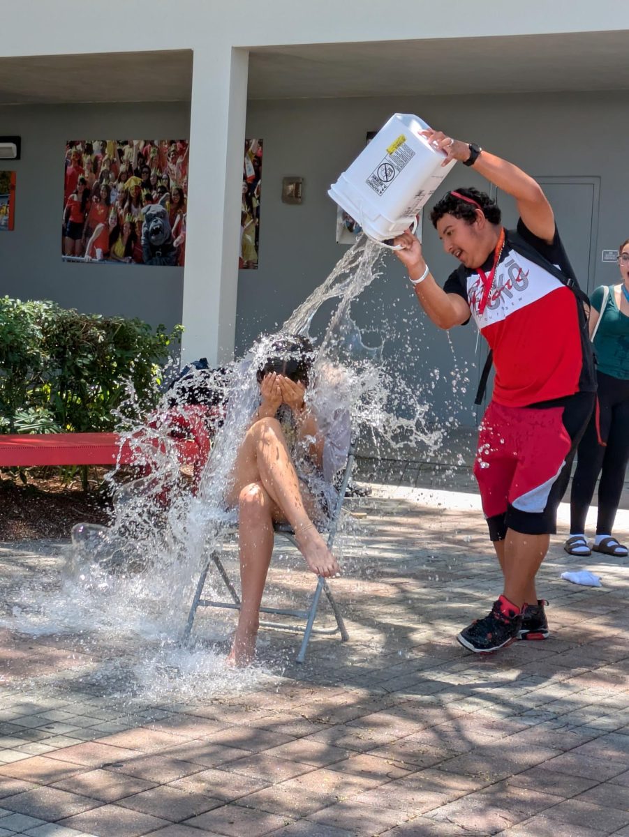 Curling into a ball to shield herself from the splash, Julicia Gamez braces as Nicklaus Cochrane dumps a gallon bucket of water on her.